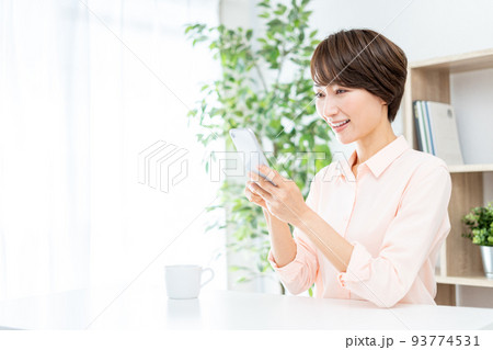 リビングでスマホを操作するミドル女性 リビングでスマホを操作するミドル女性 93774531