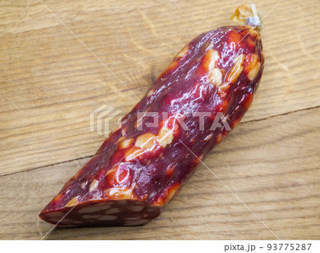 Half of an appetizing sausage on a wooden background, close-up shot. Food on a cutting board. Smoked sausage on a rustic table. Half of an appetizing sausage on a wooden background, close-up shot. Food on a cutting board. Smoked sausage on a rustic table. 93775287