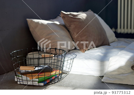Metal basket with notebooks placed near bed in apartment Metal basket with notebooks placed near bed in apartment 93775312