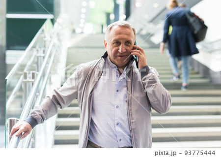Middle aged man with phone going down stairs in mall Middle aged man with phone going down stairs in mall 93775444