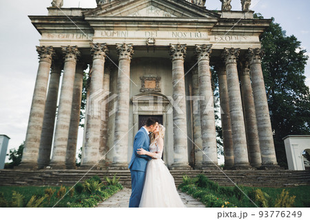 Beautiful bride and groom embracing and kissing on their wedding day outdoors 93776249