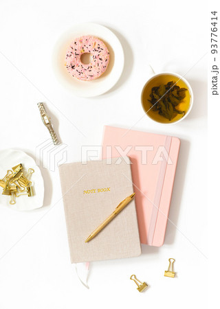 Tea break at the workplace of a freelancer or female blogger. Donat, tea in a mug, notebooks, pen on a white background. Trend background for the blog 93776414