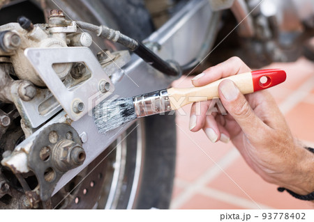 Man painting motorbike with brush at home. Renew old motorbike. Man painting motorbike with brush at home. Renew old motorbike. 93778402