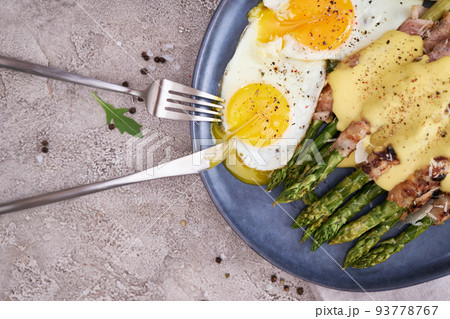 Healthy tasty breakfast - Asparagus wrapped with bacon and fried eggs on a plate Healthy tasty breakfast - Asparagus wrapped with bacon and fried eggs on a plate 93778767