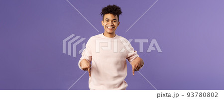 Portrait of cheerful, happy young 25s man recommending product, showing promo of product, delivery service, online shop or appllication, pointing fingers down, smiling pleased camera Portrait of cheerful, happy young 25s man recommending product, showing promo of product, delivery service, online shop or appllication, pointing fingers down, smiling pleased camera 93780802
