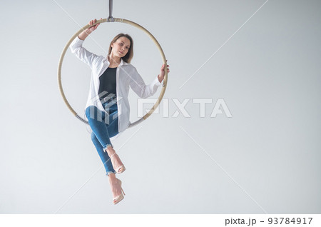 Caucasian woman gymnast on an aerial hoop takes a selfie on a smartphone.  93784917