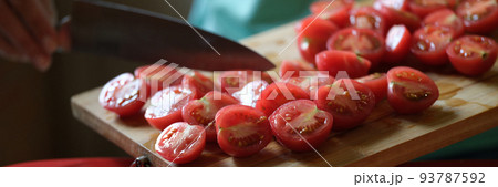Cook putting sliced tomatoes on red plate closeup 93787592