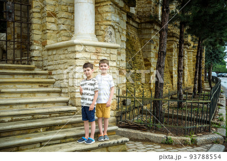 Two little boys with modern haircuts near the stairs in colorful T-shirts and single tone pants. Concept of modern little boys Two little boys with modern haircuts near the stairs in colorful T-shirts and single tone pants. Concept of modern little boys 93788554