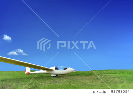 青空を背景に緑の高原に駐機する白いグライダー 93793034