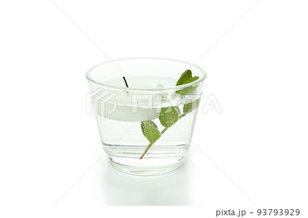 Glass of water with candle and twig isolated on white background 93793929