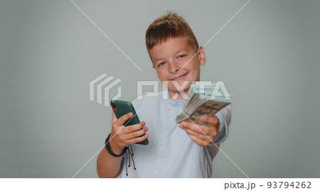 Rich toddler boy with smartphone rejoicing win, receiving money dollar cash, success lottery luck 93794262