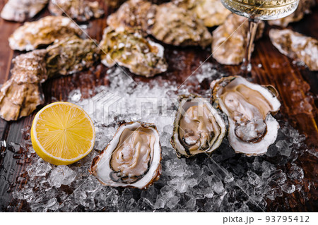 Opened oysters, ice and lemon on board 93795412
