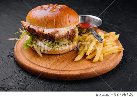 Delicious hamburger with cheese sauce and french fries on wooden table 93796420