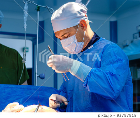 A male surgeon stitches up the patient's skin. A male surgeon stitches up the patient's skin. 93797918