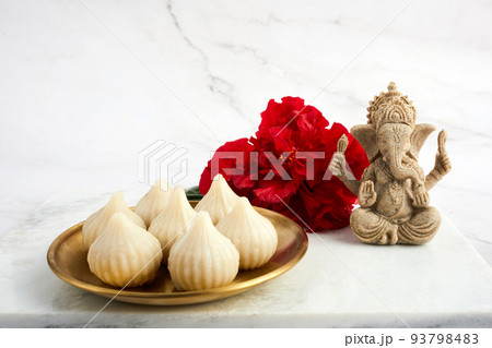 Idol of lord Ganesha with Modak Sweet Dish and flower. Ganesh chaturthi Idol of lord Ganesha with Modak Sweet Dish and flower. Ganesh chaturthi 93798483