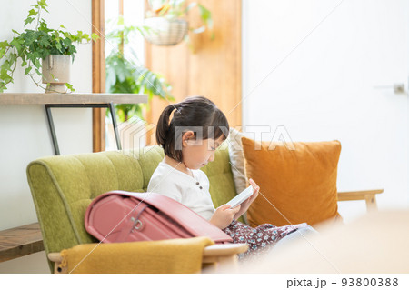 ソファでタブレットを見る小学生の女の子 93800388