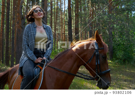 Woman in casual clothes rides a horse in hot summer day 93802106