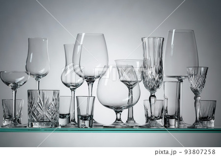 Different empty glasses on a glass shelf. 93807258