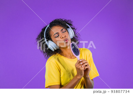 African woman singing and dancing with hair brush or comb instead microphone at purple studio 93807734
