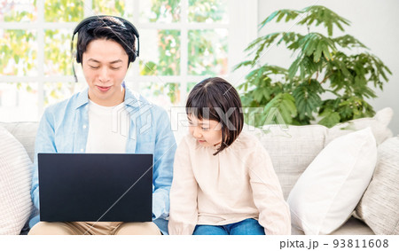 ソファに座ってノートパソコンで仕事をするパパと話しかける子供 ソファに座ってノートパソコンで仕事をするパパと話しかける子供 93811608
