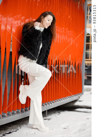 Portrait of young woman standing in winter town and posing for a photo Portrait of young woman standing in winter town and posing for a photo 93815315