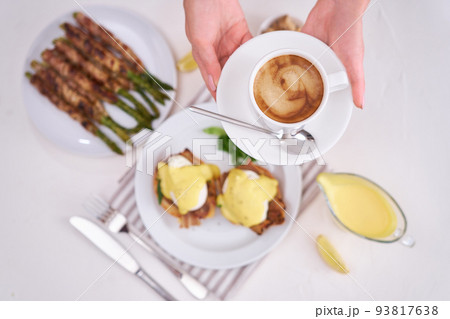 Tasty eggs Benedict, hollandaise sauce and aspargus covered with bacon 93817638