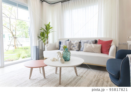 Red, blue and white pillows on a white sofa, living room interior. 93817821