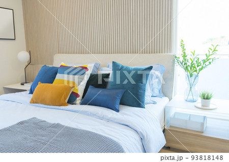 Yellow and green pillow on bed with table lamp on bedside table in modern interior bedroom. Yellow and green pillow on bed with table lamp on bedside table in modern interior bedroom. 93818148