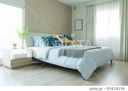 Yellow and green pillow on bed with table lamp on bedside table in modern interior bedroom. Yellow and green pillow on bed with table lamp on bedside table in modern interior bedroom. 93818156