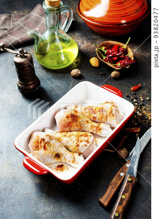 Raw uncooked chicken legs, drumsticks in bowl, meat with ingredients for cooking 93820477