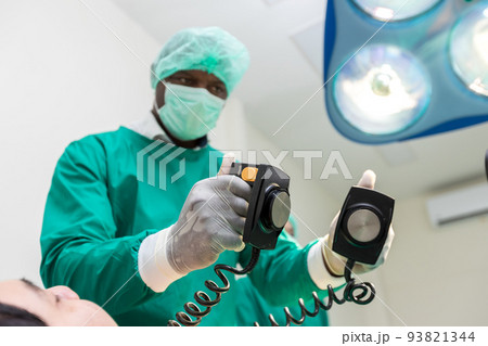 The doctor is giving a defibrillators to save the patient's life in the hospital. 93821344