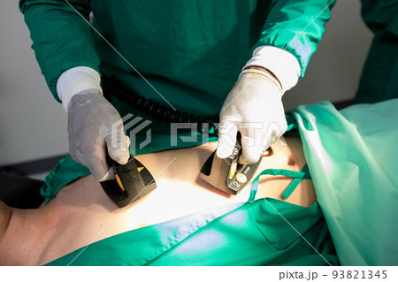 The doctor is giving a defibrillators to save the patient's life in the hospital. The doctor is giving a defibrillators to save the patient's life in the hospital. 93821345