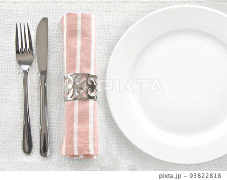 Top view white ceramic empty dish with silver fork and knife and napkin on the white tablecloth. Top view white ceramic empty dish with silver fork and knife and napkin on the white tablecloth. 93822818