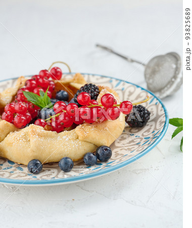 Fruit tart with red currants sprinkled with powdered sugar on a white table Fruit tart with red currants sprinkled with powdered sugar on a white table 93825689