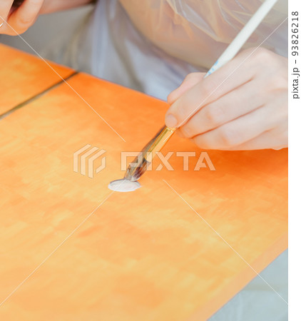 art, creativity and inspiration concept, female hand with paintbrush painting at home or studio on orange canvas. 93826218