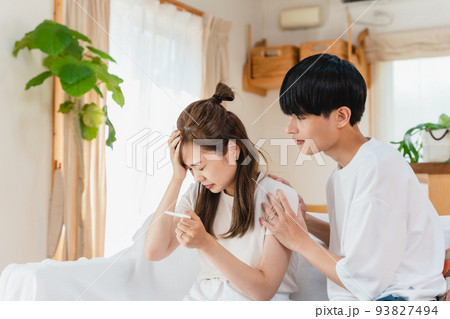 妊娠検査薬を確認する夫婦 93827494