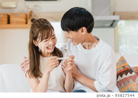妊娠検査薬を確認する夫婦 93827544