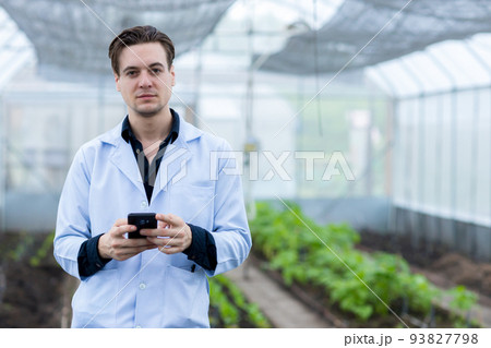 Scientist using Smart Phone. Scientist work at Vegetable Garden Lab site Scientist using Smart Phone. Scientist work at Vegetable Garden Lab site 93827798