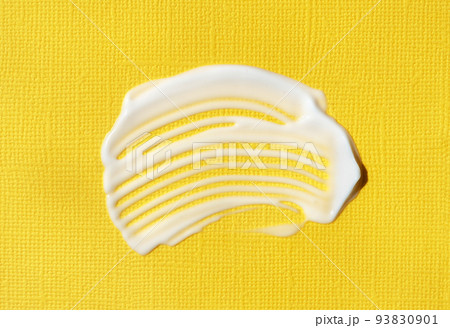 The texture of white cream on yellow background. A smear of moisturizer closeup. Lotion swatch. Beauty, skin care product smear smudge drop. SPF sunscreen cream sample The texture of white cream on yellow background. A smear of moisturizer closeup. Lotion swatch. Beauty, skin care product smear smudge drop. SPF sunscreen cream sample 93830901
