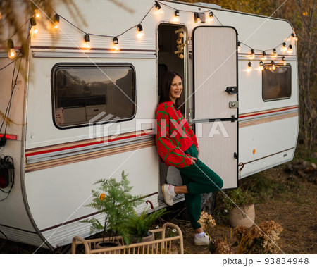 Caucasian woman in oversized red knitted jumper travels in motorhome in autumn. Caucasian woman in oversized red knitted jumper travels in motorhome in autumn. 93834948