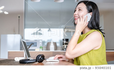 自宅で仕事をする若い女性 スマホで連絡 自宅で仕事をする若い女性 スマホで連絡 93840101