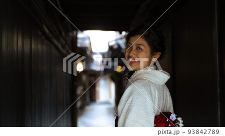 京都・祇園の路地裏　着物を着て笑顔で振り返る日本人女性　バストショット 93842789