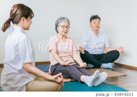 ヨガをする高齢者の男女とインストラクターの女性 93843015