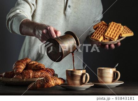 Breakfast with black coffee and fresh pastries. 93843181