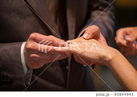 Close up of loving bride and groom putting a beautiful wedding ring to the beloved partner, marry me Close up of loving bride and groom putting a beautiful wedding ring to the beloved partner, marry me 93844943