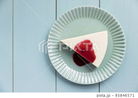 木製テーブルの上のブルーベリーソースがかかったレアチーズケーキ 93846571