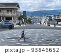 街を見下ろす坂道を横切る少女 93846652