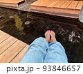 一人旅でのんびり足湯を楽しむ女性 93846657