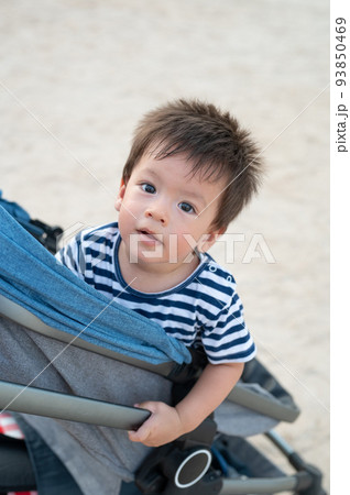 Baby boy sitting in the stroller on the beach Baby boy sitting in the stroller on the beach 93850469