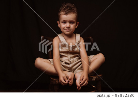 upset sad boy crying sitting on a wooden chair upset sad boy crying sitting on a wooden chair 93852230